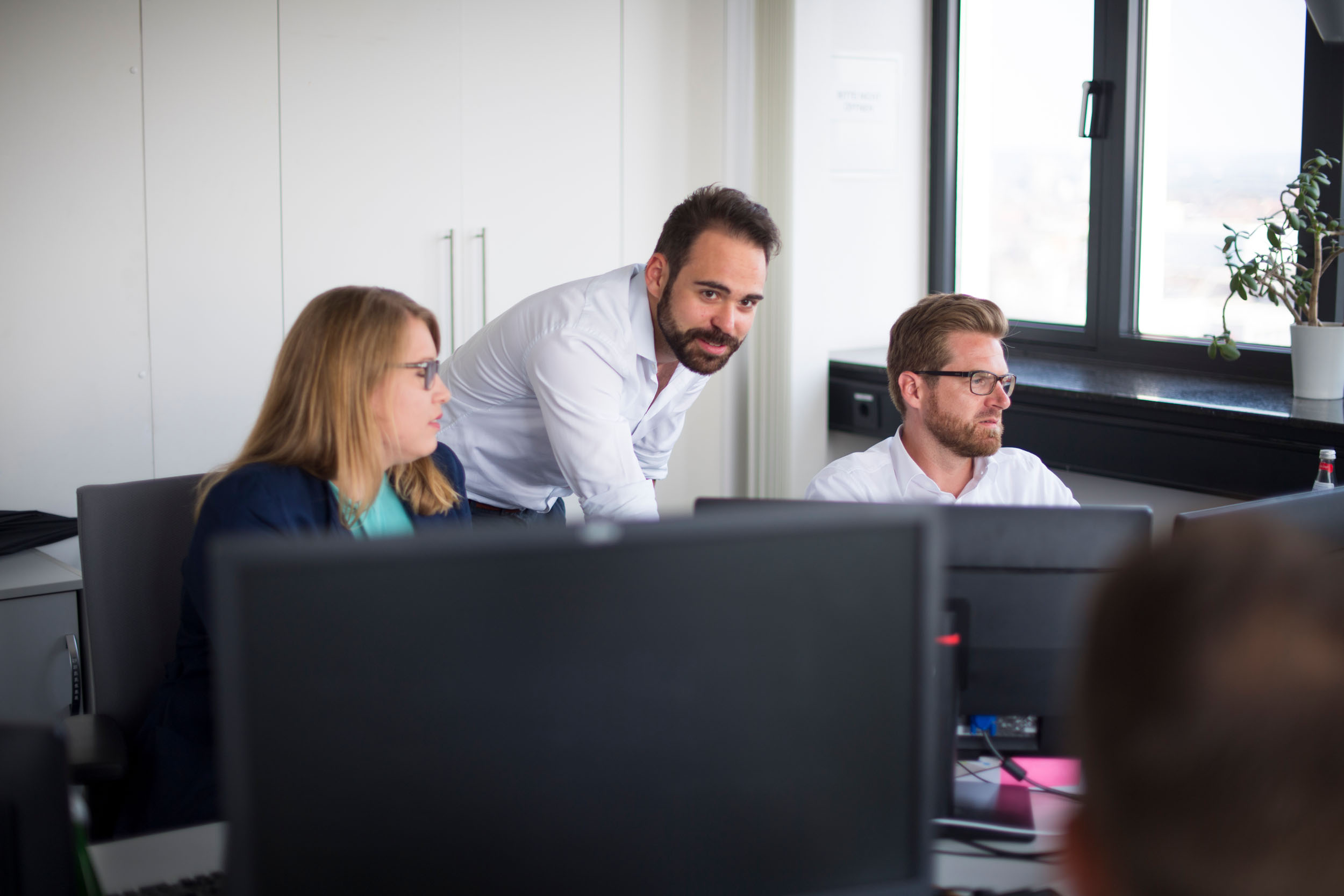 Drei Mitarbeiter an ihrem Arbeitsplatz im Büro